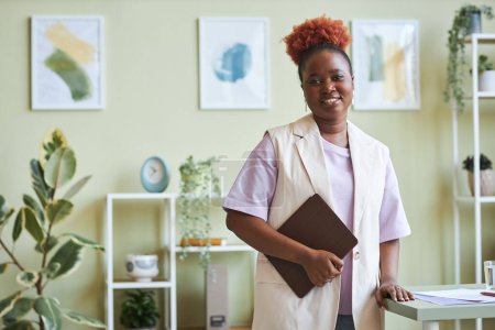 Téléchargez les photos : Portrait à la taille franche d'une femme d'affaires noire confiante regardant la caméra au bureau, les tons pastels, l'espace de copie - en image libre de droit