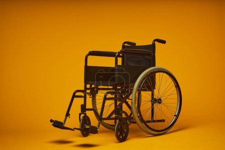 Foto de Mínimo concepto plano de silla de ruedas moderna de metal negro sobre fondo amarillo contrastado, espacio de copia - Imagen libre de derechos