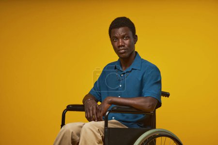 Téléchargez les photos : Portrait de jeune homme noir en fauteuil roulant et regardant la caméra en studio, espace de copie - en image libre de droit