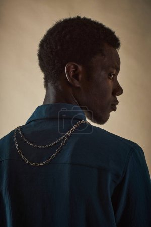 Foto de Perfil ver retrato de hombre negro joven frente a la cámara posando con cadena de metal en el cuello, concepto de accesorio de moda - Imagen libre de derechos