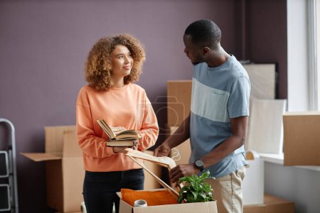 Photo for Young multiethnic family packing things in containers during relocation - Royalty Free Image