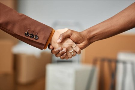 Photo for Close-up of businesswoman shaking hands with worker from moving service - Royalty Free Image