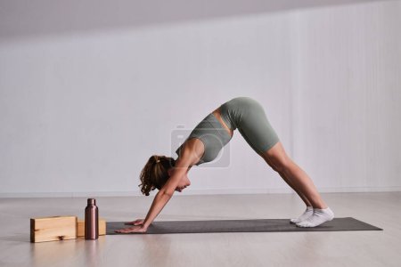 Téléchargez les photos : Jeune femme faisant des exercices d'étirement sur tapis d'exercice pendant l'entraînement sportif - en image libre de droit