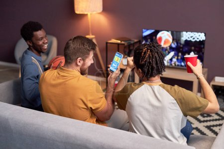 Foto de Grupo de fanáticos del deporte viendo partidos de baloncesto en casa en la televisión y animando - Imagen libre de derechos