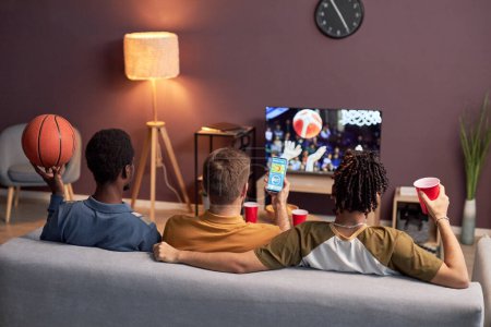 Téléchargez les photos : Vue arrière du groupe d'amis regardant le match sportif à la maison et buvant de la bière - en image libre de droit