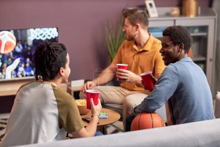 Foto de Diverso grupo de hombres viendo partidos deportivos en la televisión en casa y bebiendo cerveza - Imagen libre de derechos