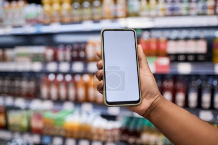 Téléchargez les photos : Gros plan d'un smartphone portable féminin avec maquette d'écran blanc dans un supermarché, espace de copie - en image libre de droit