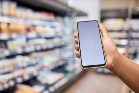 Téléchargez les photos : Gros plan de la main féminine montrant smartphone avec maquette d'écran vierge dans l'intérieur du supermarché - en image libre de droit