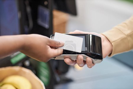 Foto de Primer plano de mujer negra irreconocible pagando a través de tarjeta de crédito maqueta en el supermercado, espacio de copia - Imagen libre de derechos