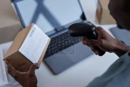 Photo for Hand of young African American male worker of post office scanning code on box while checking information about receiver name and address - Royalty Free Image