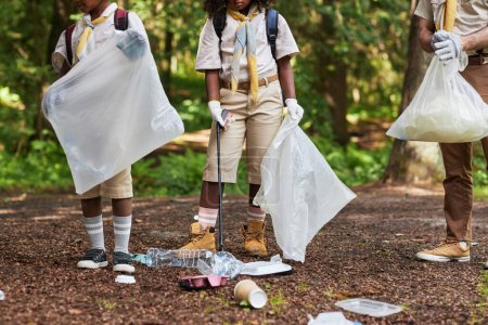 Téléchargez les photos : Section basse du groupe de scouts ramassant des ordures dans la forêt lors d'une sortie de sensibilisation à l'éco - en image libre de droit