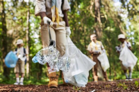 Foto de Primer plano de los exploradores recogiendo basura en el bosque durante la excursión de conciencia ecológica, espacio de copia - Imagen libre de derechos