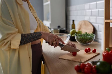 Photo for Side view closeup of pregnant woman cooking healthy meal and cutting vegetables in kitchen - Royalty Free Image