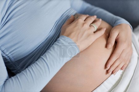 Téléchargez les photos : Gros plan de la jeune femme enceinte avec les mains sur le ventre, tons bleu pastel - en image libre de droit