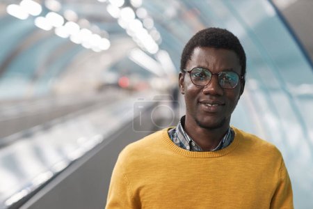Foto de Retrato del hombre afroamericano con anteojos sonriendo a la cámara mientras estaba de pie en la escalera mecánica en el metro - Imagen libre de derechos
