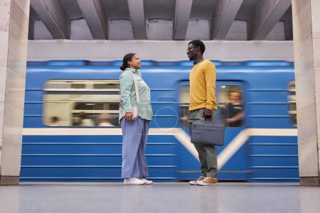 Téléchargez les photos : Couple afro-américain se réunissant dans le métro et parlant en attendant le train - en image libre de droit
