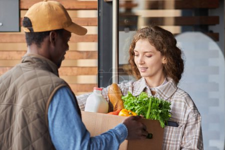 Photo for Waist up portrait of young woman receiving grocery delivery outdoors and holding bag with fresh vegetables - Royalty Free Image