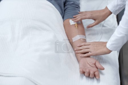 Téléchargez les photos : Gros plan de l'infirmière qui fait goutte-à-goutte pour le patient âgé pendant le traitement à l'hôpital - en image libre de droit