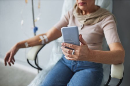 Foto de Primer plano de la mujer mayor utilizando el teléfono inteligente durante el tratamiento de quimioterapia, espacio para copiar - Imagen libre de derechos