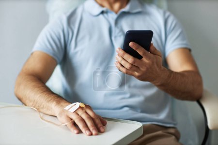 Foto de Primer plano del hombre irreconocible usando un teléfono inteligente durante el tratamiento de quimioterapia, espacio para copiar - Imagen libre de derechos