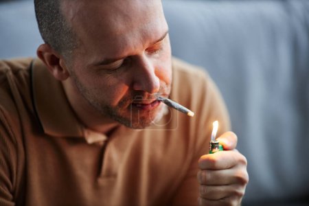 Photo for Adult man lighting up cigarette smoking at home for therapeutic purpose and medical treatment - Royalty Free Image