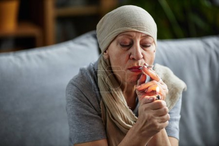 Photo for Portrait of bald adult woman lighting up cigarette at home smoking for therapeutic purpose and medical treatment, copy space - Royalty Free Image