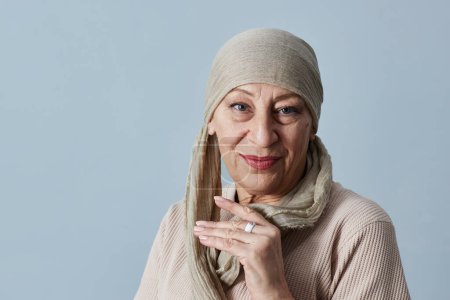 Téléchargez les photos : Portrait minimal de belle femme mature portant le foulard et le maquillage en regardant la caméra en studio - en image libre de droit
