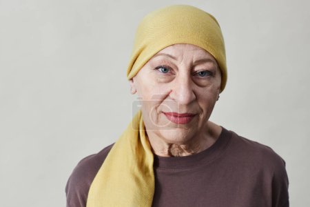 Foto de Retrato de vista frontal de una mujer adulta sonriente con pañuelo en la cabeza y mirando a la cámara contra el blanco - Imagen libre de derechos