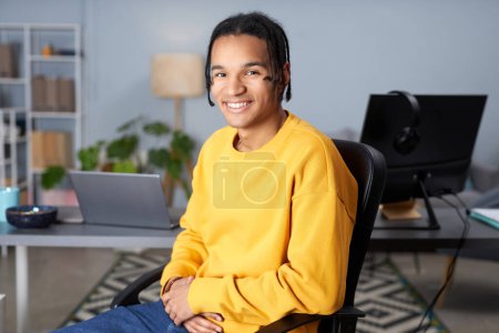 Foto de Retrato de un joven negro con capucha de color amarillo brillante posando en el lugar de trabajo y mirando a la cámara - Imagen libre de derechos