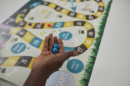 Photo for Top view closeup of male hand holding dice ready to make a move in board game, copy space - Royalty Free Image