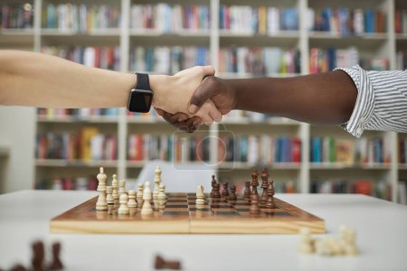 Téléchargez les photos : Vue de côté gros plan de deux joueurs d'échecs serrant la main sur l'échiquier après le match - en image libre de droit