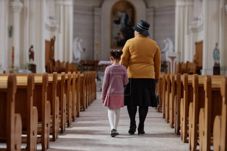 Téléchargez les photos : Vue arrière de grand-mère visitant l'église avec sa petite-fille - en image libre de droit