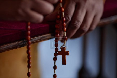 Foto de Primer plano de la mujer afroamericana sosteniendo cuentas de rosario mientras lee la oración en la iglesia - Imagen libre de derechos