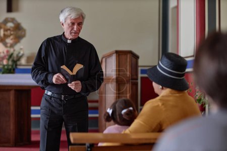 Téléchargez les photos : Grand prêtre debout avec le sermon de lecture de la Bible pour les gens dans l'église - en image libre de droit