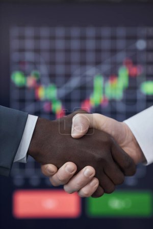 Vertikales Bild von Kollegen beim Händeschütteln zum Abschluss eines Deals während des Aktienhandels