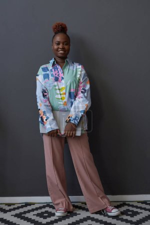 Foto de Imagen vertical de la mujer afroamericana de pie con el ordenador portátil y sonriendo a la cámara - Imagen libre de derechos