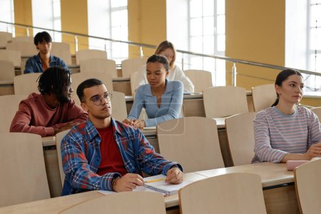Foto de Grupo de estudiantes universitarios sentados en el escritorio en la conferencia y escuchando al profesor en la sala de conferencias - Imagen libre de derechos