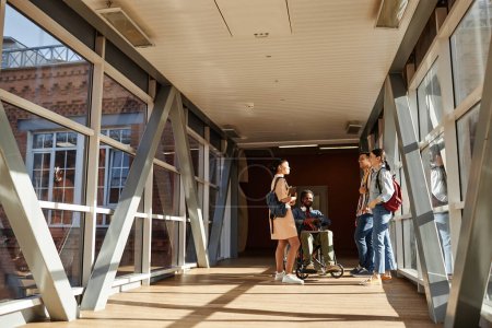 Téléchargez les photos : Groupe d'étudiants bavarder après les cours tout en se tenant dans le bâtiment moderne du collège - en image libre de droit