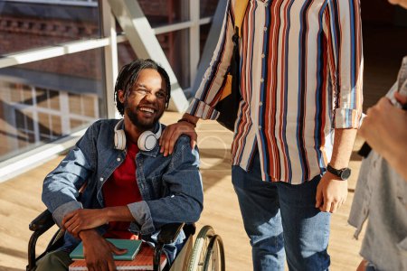 Photo for African American student with disability talking to his classmates during break at college - Royalty Free Image