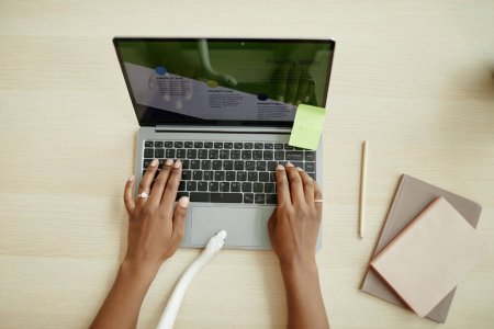 Foto de Vista superior de serpiente blanca arrastrándose entre las manos de la joven mujer de negocios afroamericana escribiendo en el teclado del ordenador portátil por escritorio - Imagen libre de derechos