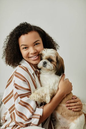 Téléchargez les photos : Portrait vertical à la taille de jeune femme noire tenant un chien mignon et souriant à la caméra - en image libre de droit
