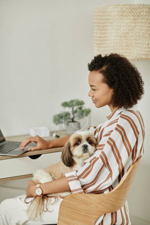 Porträt einer schwarzen jungen Frau, die von zu Hause aus mit Hund auf dem Schoß arbeitet