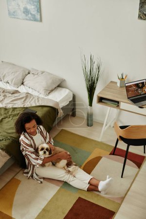 Vertikale Draufsicht auf junge Frau, die zu Hause auf dem Boden sitzt und mit kleinem Hund kuschelt im gemütlichen Innenraum, Kopierraum