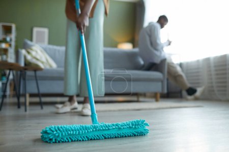 Foto de Primer plano de ama de casa limpiando el piso con fregona durante las tareas domésticas en la sala de estar - Imagen libre de derechos