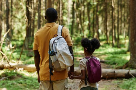 Foto de Vista trasera de la familia de dos con mochilas de senderismo en el bosque juntos en el día de verano - Imagen libre de derechos