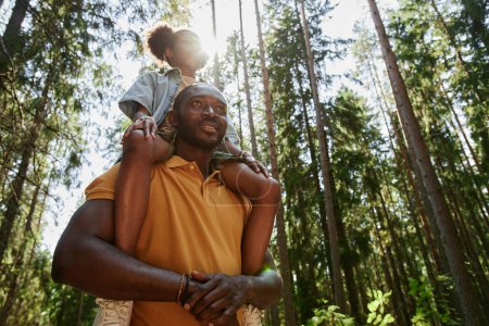 Photo for Low angle view of African American family of two walking together in the forest - Royalty Free Image
