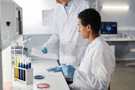 Foto de Retrato de vista lateral de dos científicos que trabajan con documentos en laboratorio, espacio de copia - Imagen libre de derechos