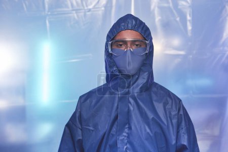 Photo for Waist up portrait of male scientist wearing full protective suit in laboratory or hospital and looking at camera over mask - Royalty Free Image