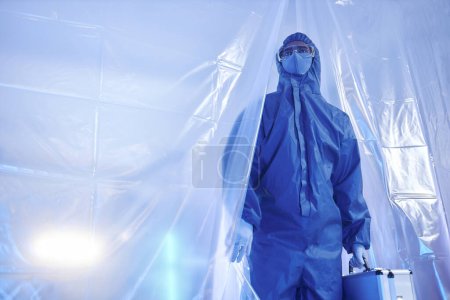 Photo for Blue tone portrait of scientist or medical worker wearing full protective suit entering biohazard danger zone - Royalty Free Image