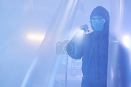 Foto de Retrato en tono azul del científico o trabajador médico que usa un traje de protección completo que entra en la zona de peligro biológico con linterna - Imagen libre de derechos